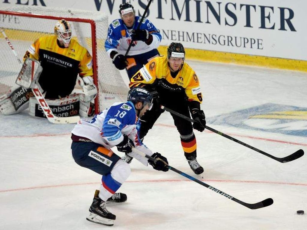 Slowakeis Andrej Kudrna (M) versucht, den Puck vorbei an Deutschlands Bernhard Ebner (r) ins Tor zu schießen. Foto: Monika Skolimowska