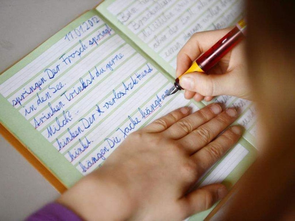 Ein Mädchen übt in ihrem Schreibheft die deutsche Rechtschreibung. Foto: Jens Kalaene