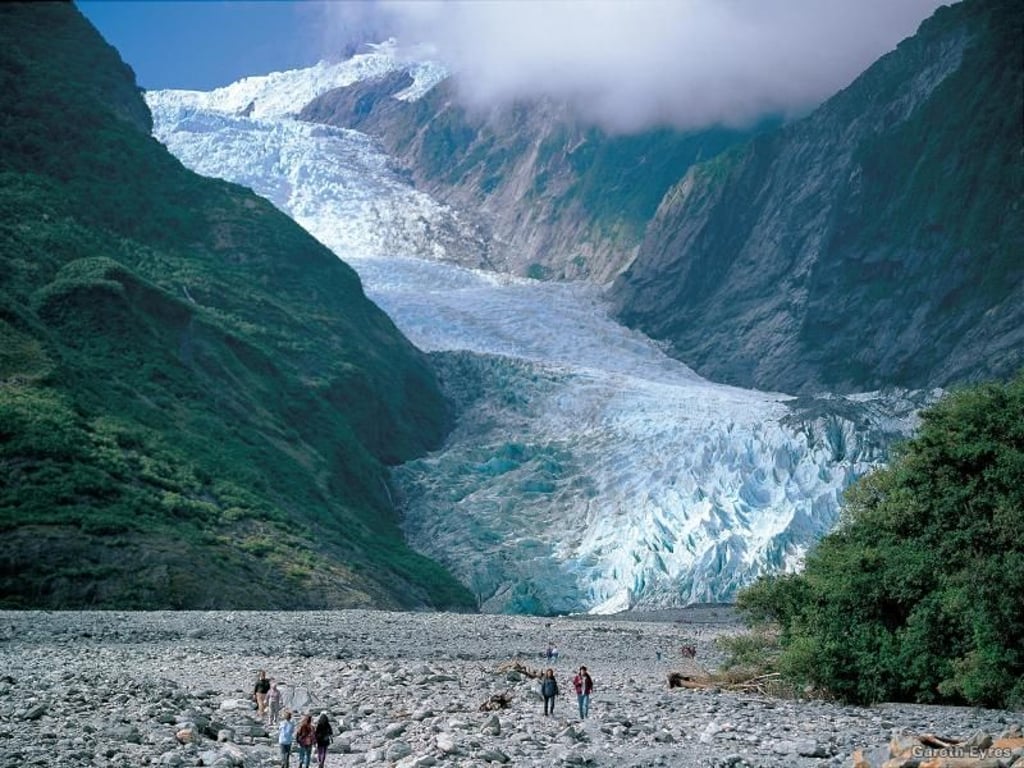 Die großartigen Landschaften lockten Regisseur Peter Jackson nach Neuseeland, der nach Drehorten für die Herr-der-Ringe-Trilogie suchte. Hier sieht man Touristen vor dem gewaltigen Franz-Joseph-Gletscher, den sich Urlauber auch aus der Luft anschauen können. Foto: Tourism New Zealand/Gareth Eyres