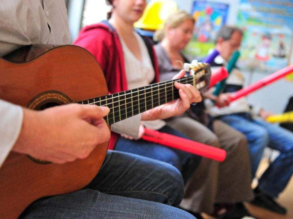 Ein Musiklehrer spielt Gitarre. Foto: Marc Tirl/Archiv