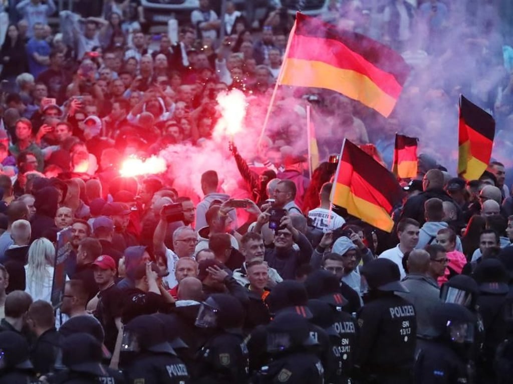 Demonstranten zünden in Chemnitz Pyrotechnik und schwenken Deutschlandfahnen. Foto: Jan Woitas