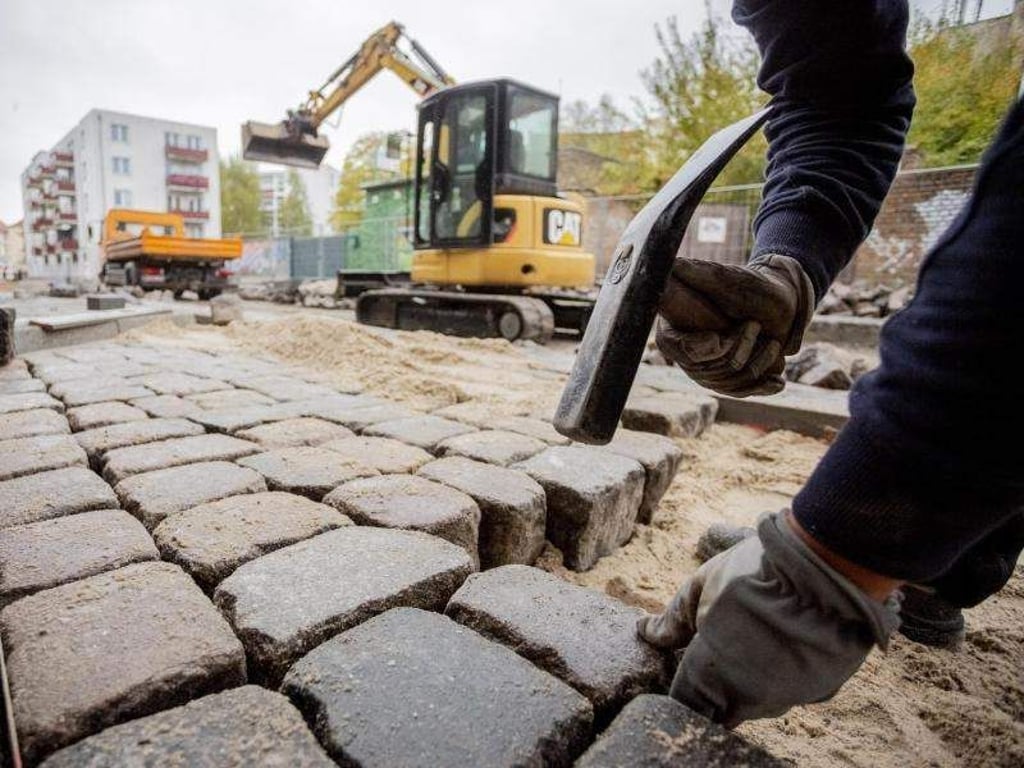 Ein Bauarbeiter setzt Pflastersteine. Foto: Christoph Soeder/Archiv