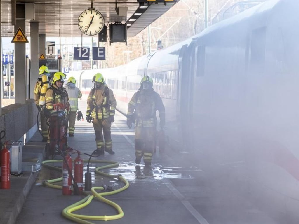 Feuerwehrleute stehen an einem in Brand geratenen ICE im Hauptbahnhof Hannover. Foto: Clemens Heidrich