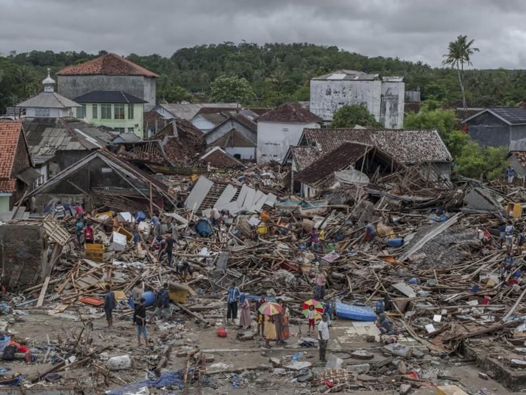 Menschen untersuchen die Schäden in einem verwüsteten Dorf. Foto: Fauzy Chaniago/AP
