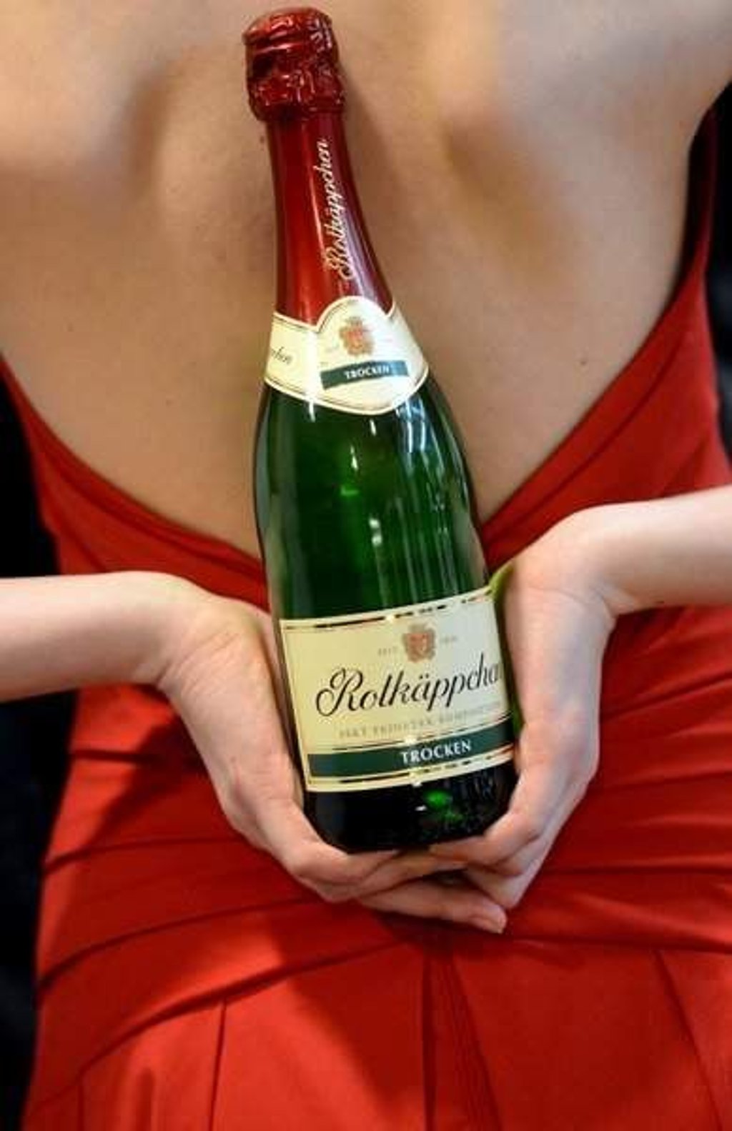 ARCHIV - Ein Model der Rotkäppchen-Mumm Sektkellerei posiert am 16.04.2013 mit einer Sektflasche der Marke Rotkäppchen auf der Pressekonferenz des Unternehmens in Leipzig (Sachsen). Foto: Hendrik Schmidt/dpa (zu dpa "25 Jahre nach der Wiedereinigung: Ostmarken erobern den Westen" am 01.11.2014) +++(c) dpa - Bildfunk+++