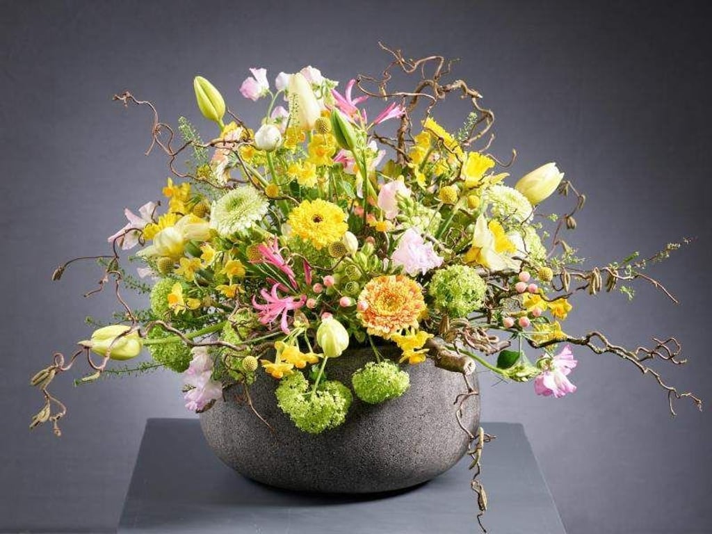 Dieser farbenfrohe Osterstrauß besteht unter anderem aus Mini-Narzissen, Ranunkeln und Tulpen. Zweige der Korkenzieher-Hasel lockern das Gesteck auf. Foto: Fachverband Deutscher Floristen e.V./J. Manegold