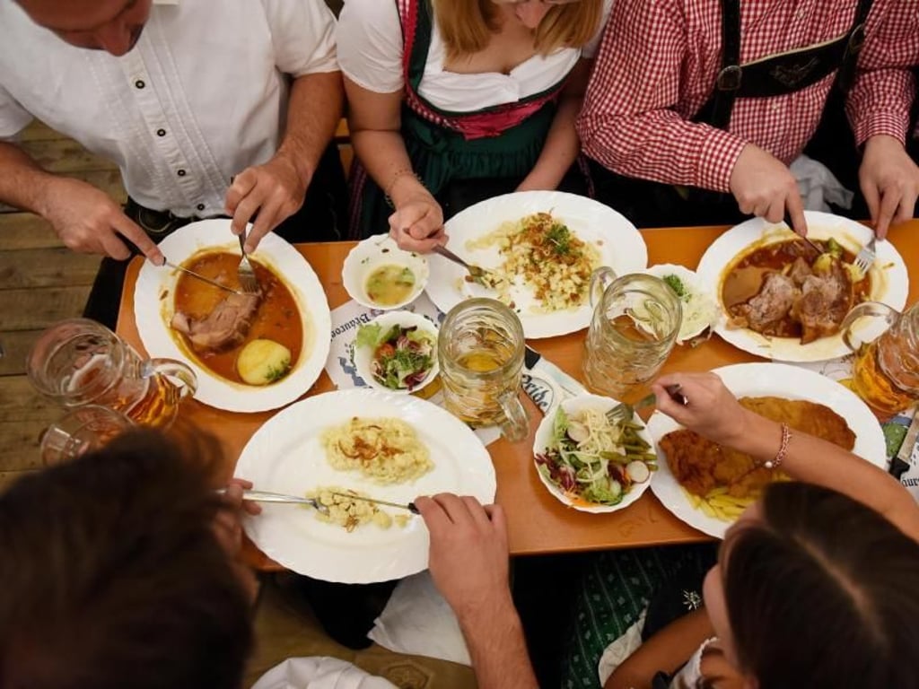 Gäste essen in einem Zelt auf dem Oktoberfest. Foto: Angelika Warmuth