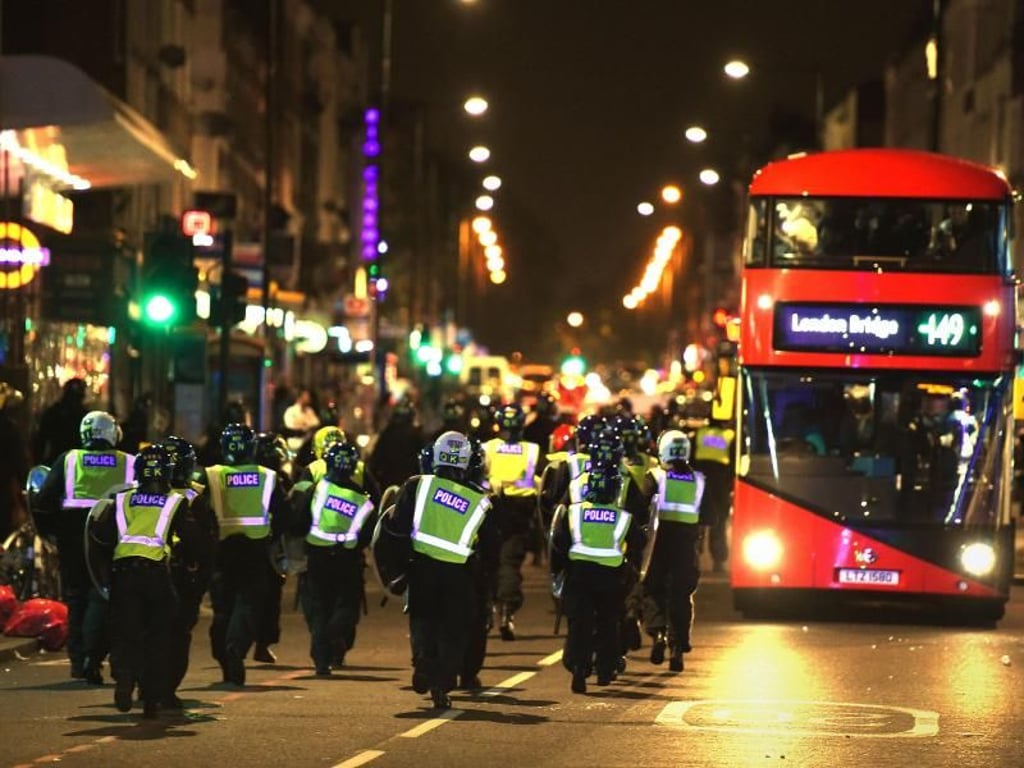 Polizisten passieren bei ihrem Einsatz in Hackney einen roten Doppeldeckerbus. Foto: Lauren Hurley
