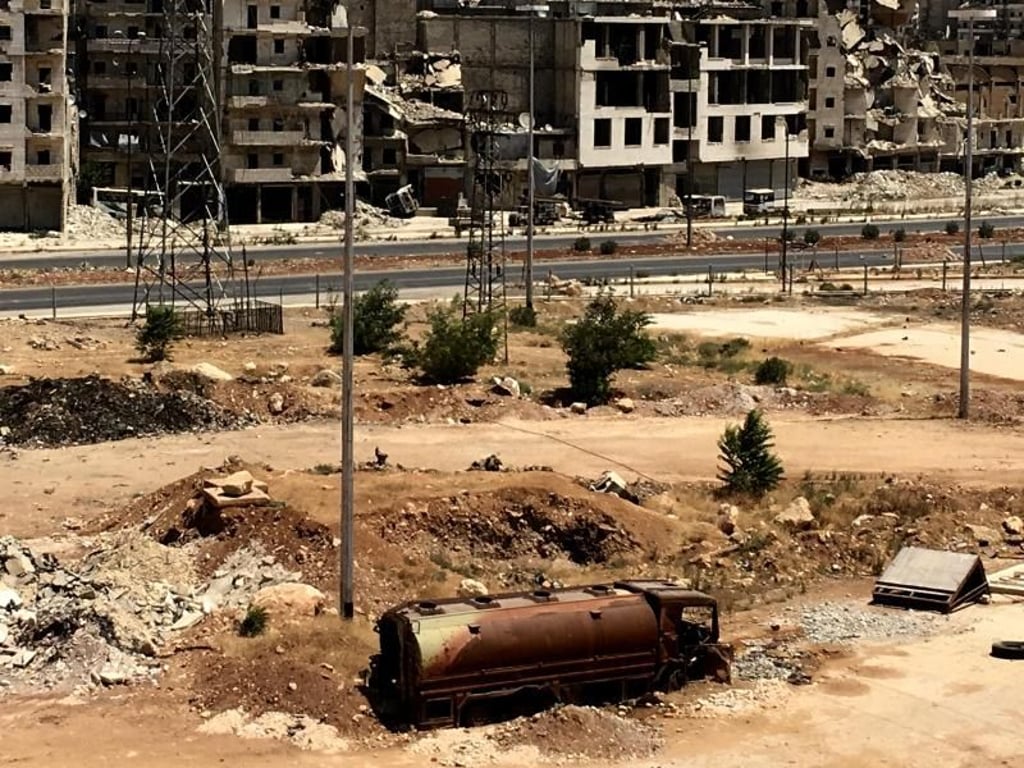 Ein ausgebrannter Tanklastzug steht vor zerstörten Gebäuden im südlichen Vorort Al-Ramouseh von Aleppo. Foto: Michael Alaeddin/Sputnik