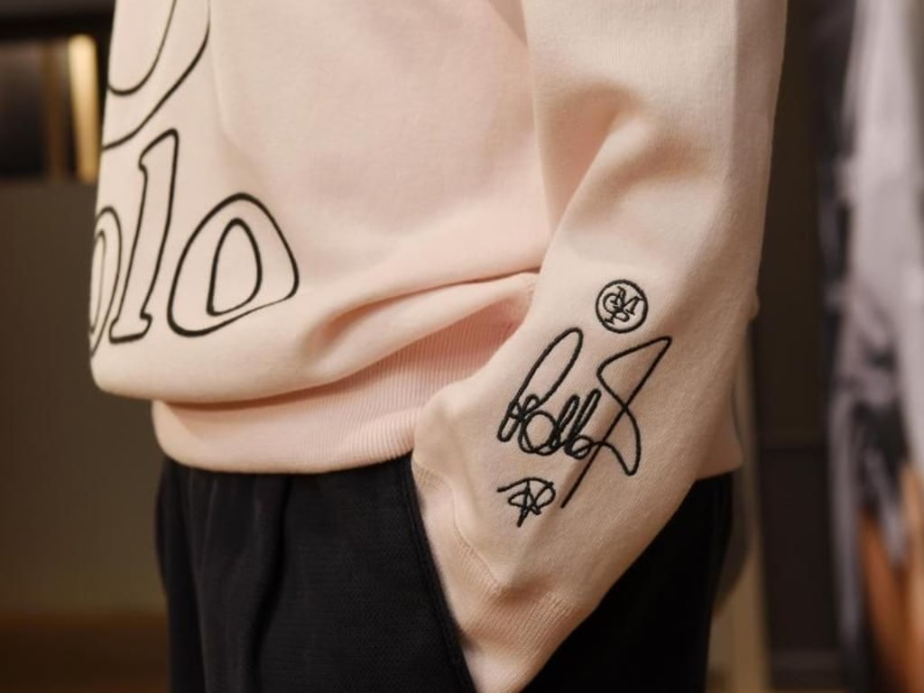 Eine aufgedruckte Unterschrift von Robbie Williams auf einem Sweatshirt seiner Kollektion. Foto: Sven Hoppe/dpa