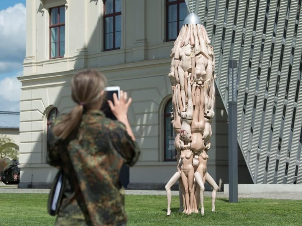 Eine Frau in Uniform fotografiert die fünf Meter hohe Rakete «Crazy Daisy» der Künstlerin Birgit Dieker. Foto: Sebastian Kahnert