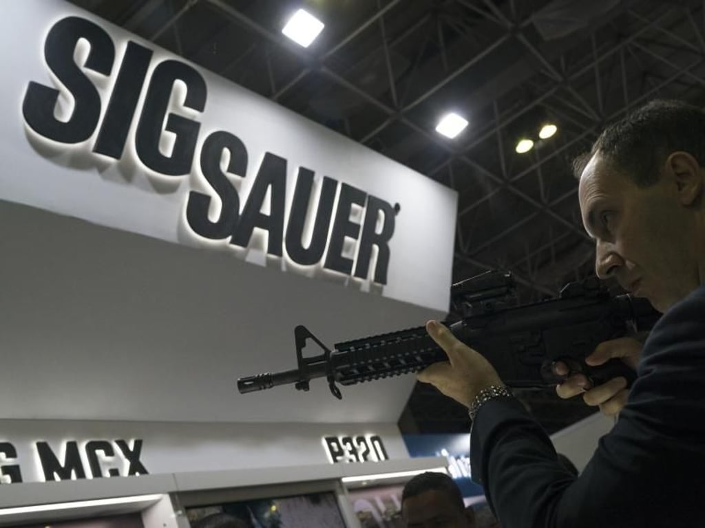 Ein Mann testet auf einer Waffenmesse ein Sig-Sauer-Gewehr. Foto: Leo Correa/AP