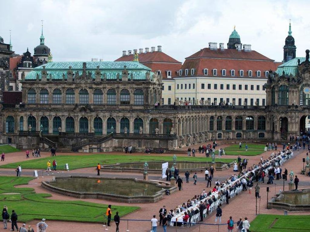 Ehrenamtliche sitzen an einer 100 Meter langen Kaffeetafel im Zwinger in Dresden. Foto: Arno Burgi