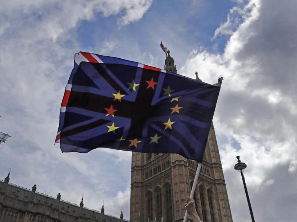 Ein Demonstrant schwenkt vor den Parlamentsgebäuden in Westminster eine britische und eine EU-Fahne. Foto: Frank Augstein/AP