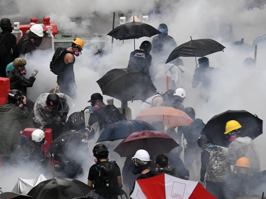 Demonstranten versuchen sich vor Tränengas zu schützen. Foto: kyodo