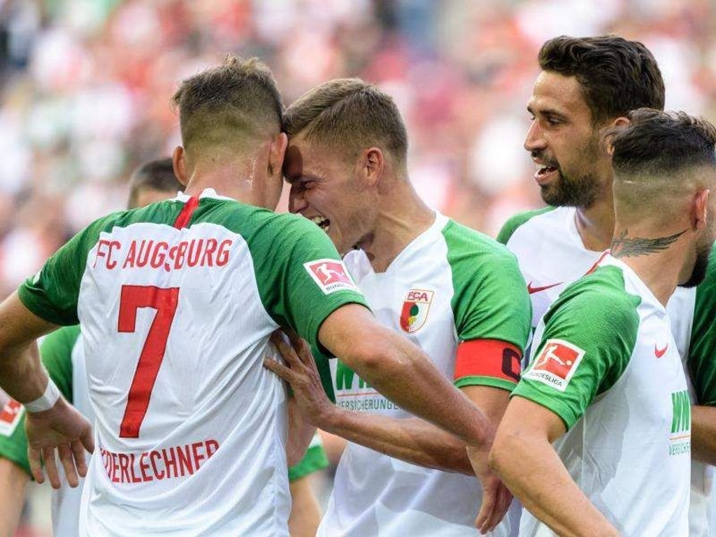 Augsburgs Torschütze Florian Niederlechner (l) und Alfred Finnbogason jubeln mit der Mannschaft über den Treffer zum 2:0. Foto: M. Balk