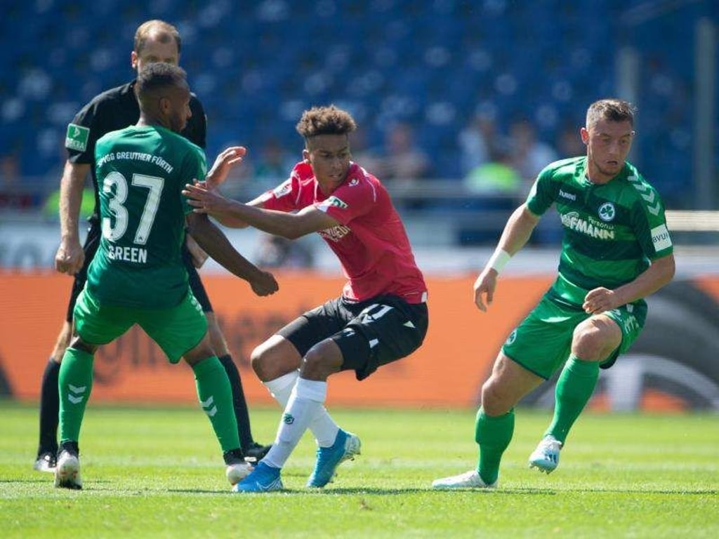 Hannovers Linton Maina (M) wird von den Fürthern Julian Green (l) und Fürths Maximilian Wittek umstellt. Foto: Swen Pförtner