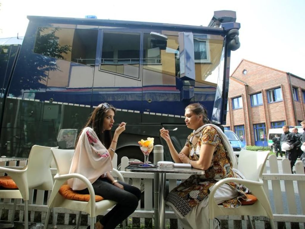 Direkt neben einem Wasserwerfer genießen zwei Frauen ihren Eisbecher in einem Dortmunder Café. Foto: Roland Weihrauch