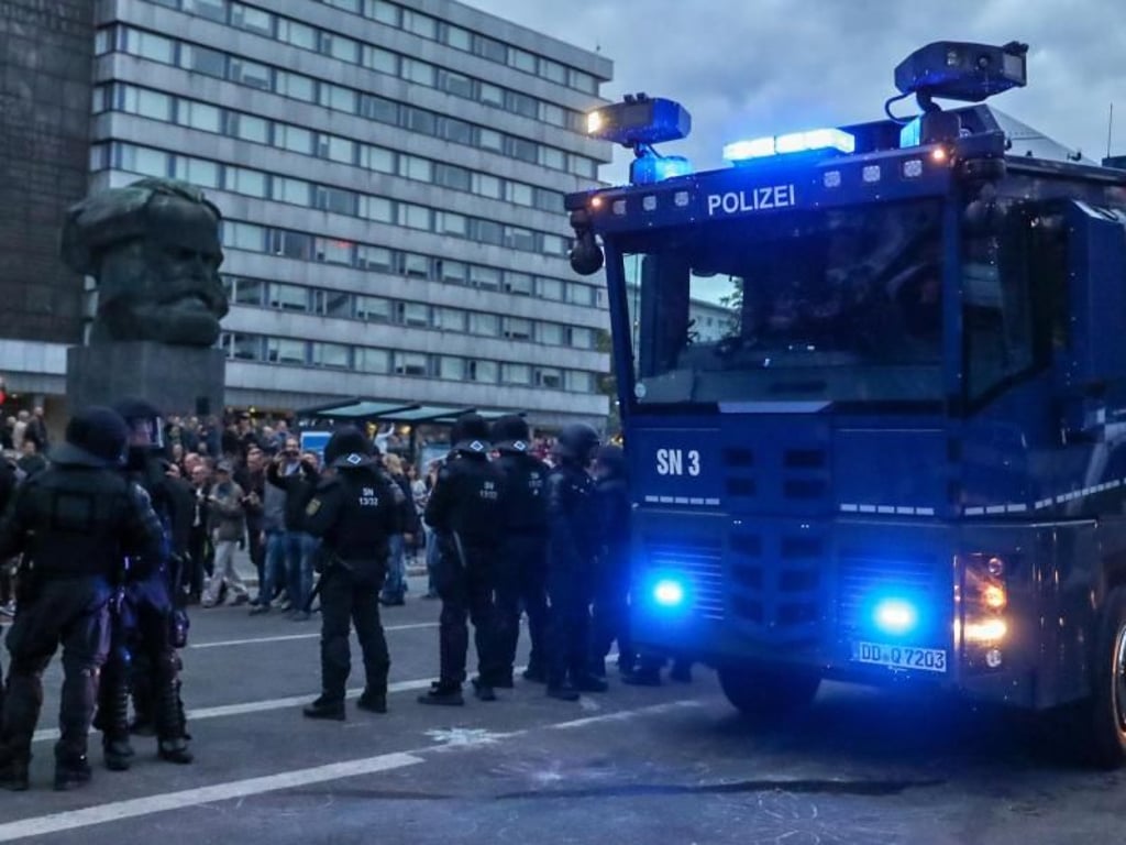 Polizisten sichern mit einem Wasserwerfer eine Demonstration der rechten Szene vor dem Karl-Marx-Denkmal in Chemnitz. Foto: Jan Woitas