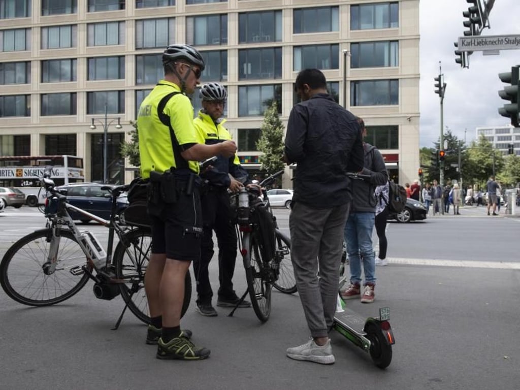 Und noch eine neue Aufgabe: Polizisten der Berliner Fahrradstaffel kontrollieren auf einem Bürgersteig zwei Jugendliche mit E-Tretrollern. Foto: Paul Zinken