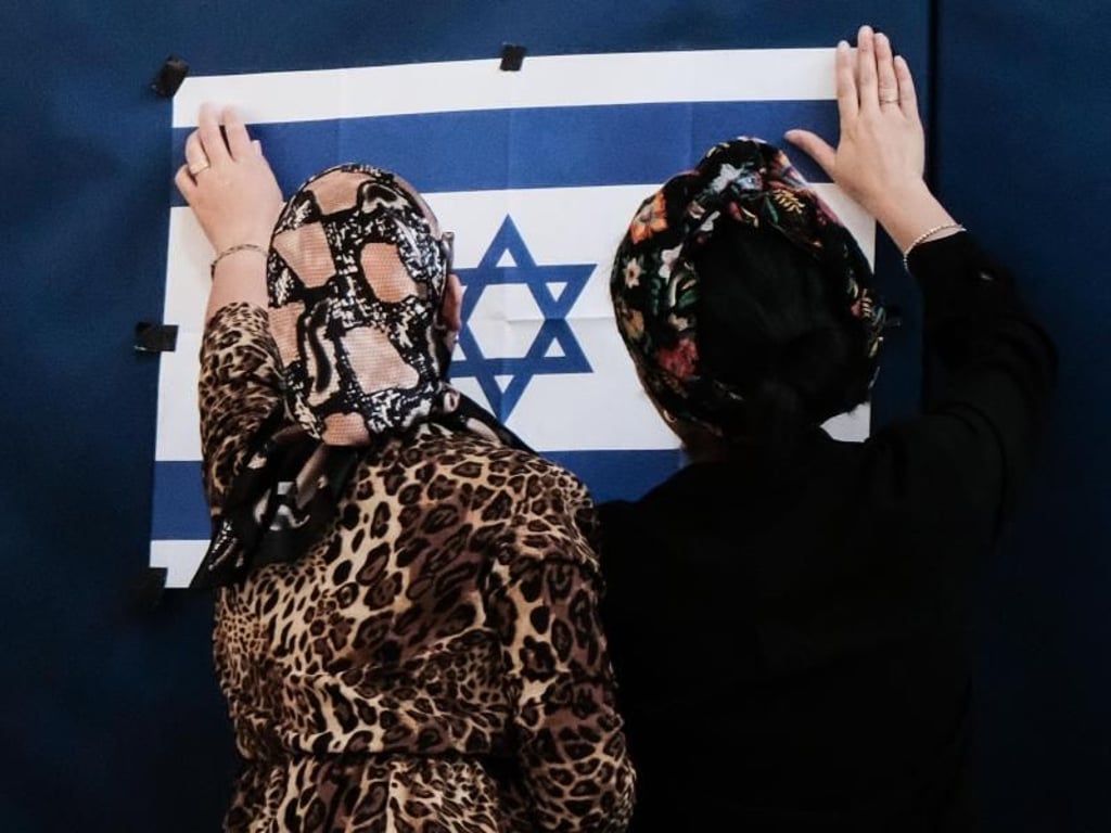 Zwei Mitarbeiterinnen des Wahlausschusses befestigen in einem Wahllokal in Jerusalem eine israelische Fahne. Foto: Nir Alon/ZUMA Wire