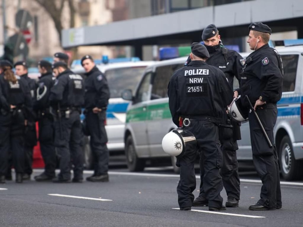 Polizisten warten vor dem Beginn einer Kurden-Demo gegen die türkische Militäroffensive in Nordsyrien in Köln an ihren Fahrzeugen. Foto: Marius Becker