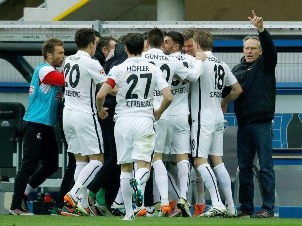 freiburgs Spieler und Trainer Christian Streich (r) feiern den Aufstieg durch den 2:1-Sieg beim SC Paderborn. Foto: Ina Fassbender