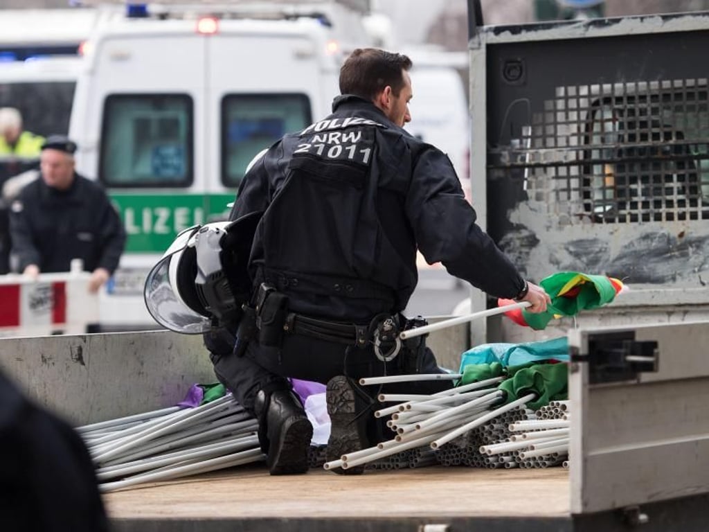 Ein Polizist kontrolliert in Köln die Fahnen auf der Lagerfläche eines Lieferwagens. Foto: Marius Becker