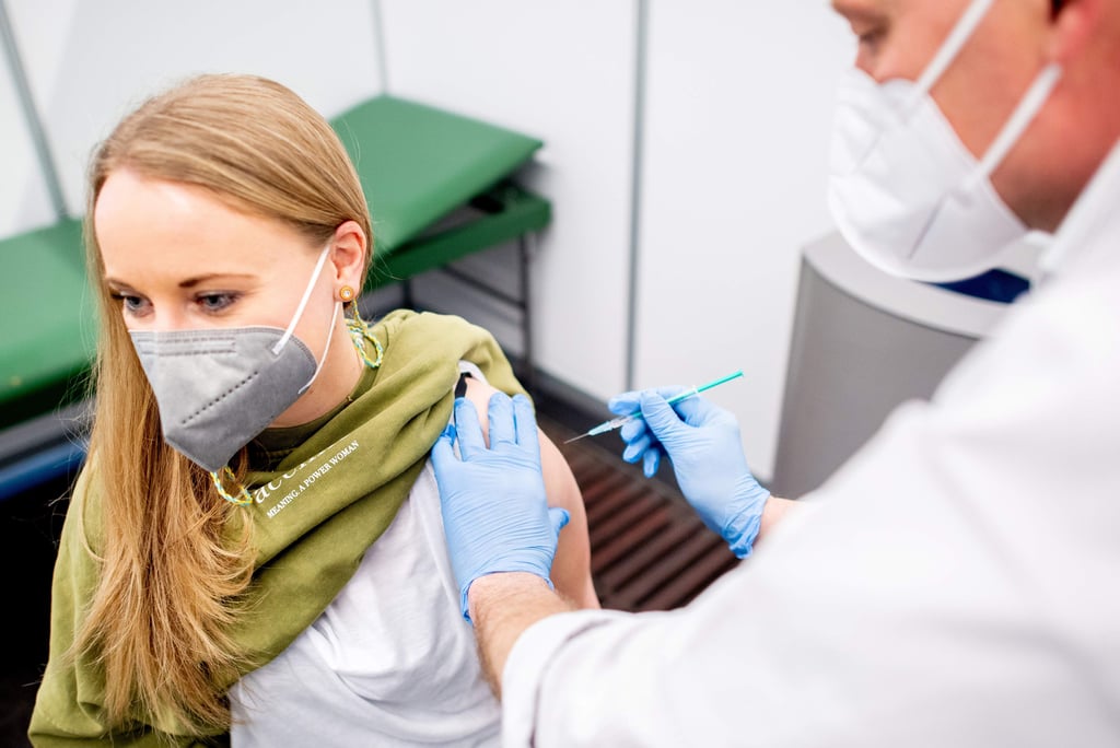 26.02.2021, Bremen: Marie Rohlfs, Erzieherin im Kindergarten Sternschnuppe, erhält vom Impfberechtigten Thomas Holler im Impfzentrum in der Messehalle ihre Impfung mit dem Impfstoff von AstraZeneca. Die Gesundheitsbehörden in Bremen haben nach dem Beschluss der Gesundheitsministerkonferenz von Anfang der Woche bereits die ersten Erzieherinnen und Erzieher aus Kindertagseinrichtungen geimpft. Foto: Hauke-Christian Dittrich/dpa Pool/dpa +++ dpa-Bildfunk +++