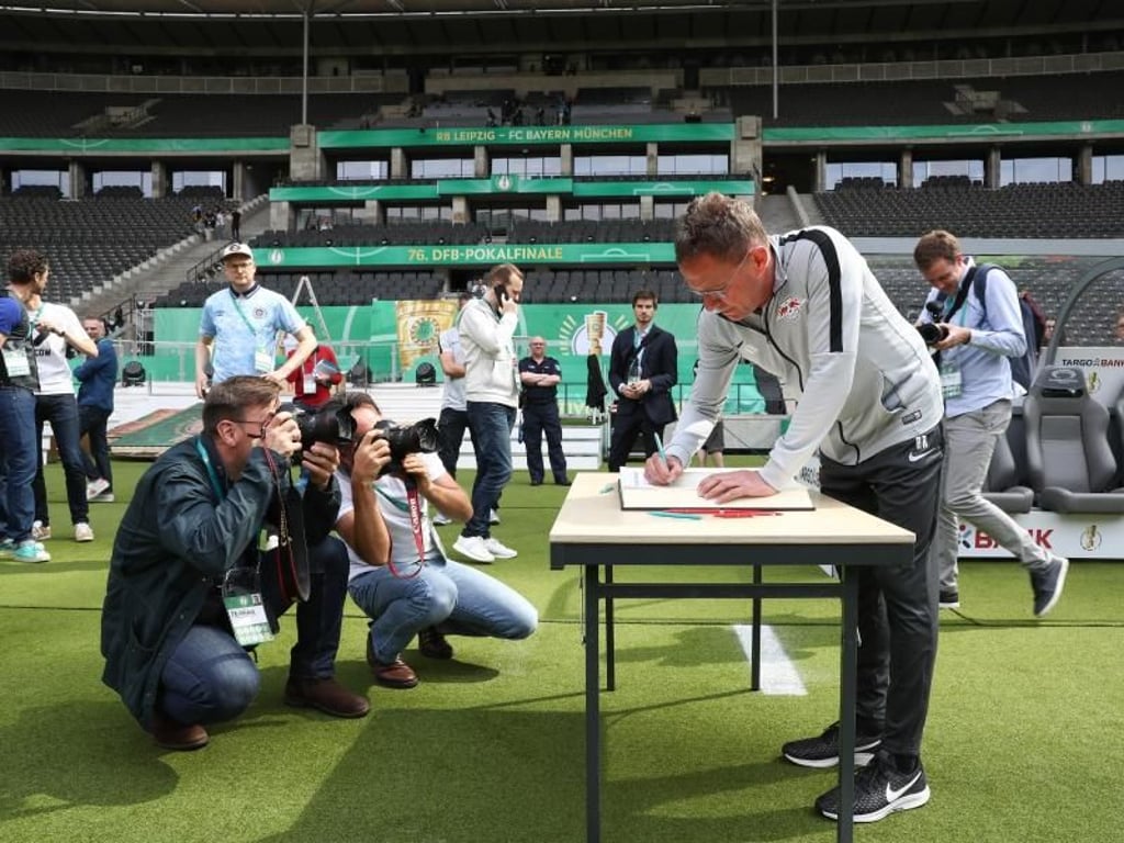 Leipzigs Trainer Ralf Rangnick schreibt in ein Erinnerungsbuch des Olympiastadions. Foto: Christian Charisius