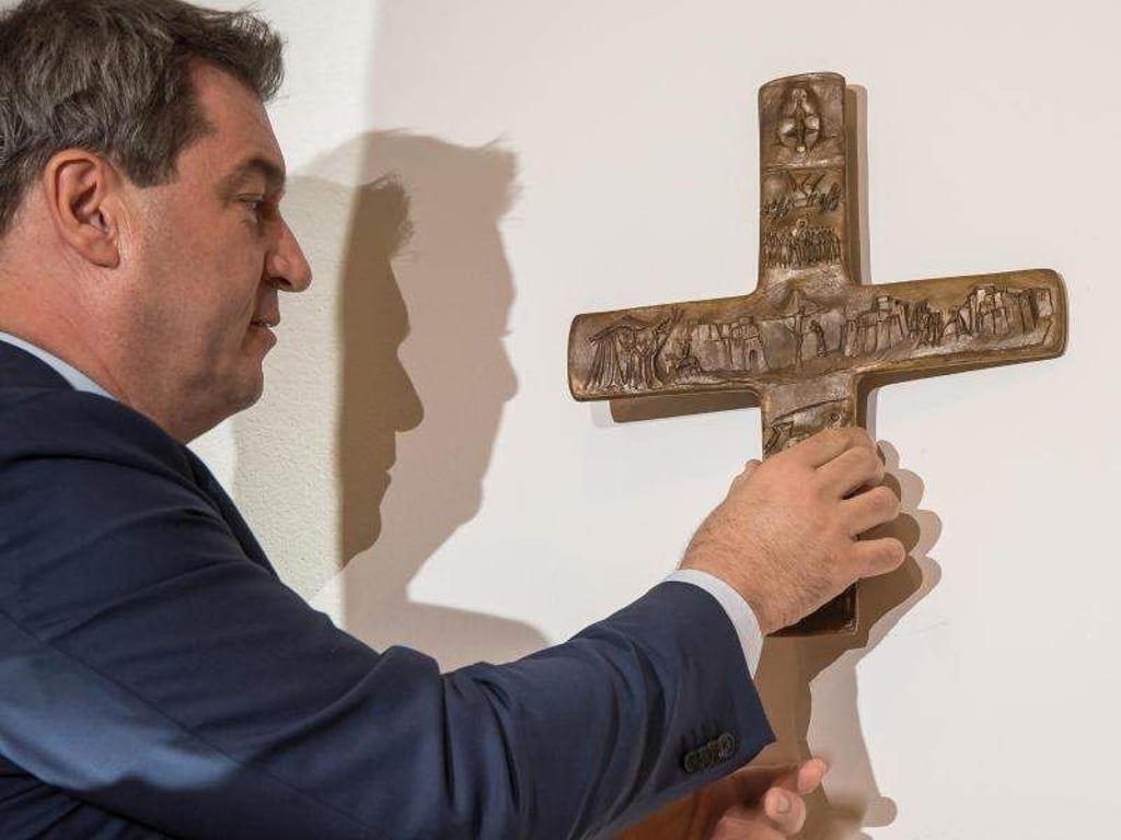 Bayerns Ministerpräsident Markus Söder hängt ein Kreuz im Eingangsbereich der bayerischen Staatskanzlei auf. Foto: Peter Kneffel