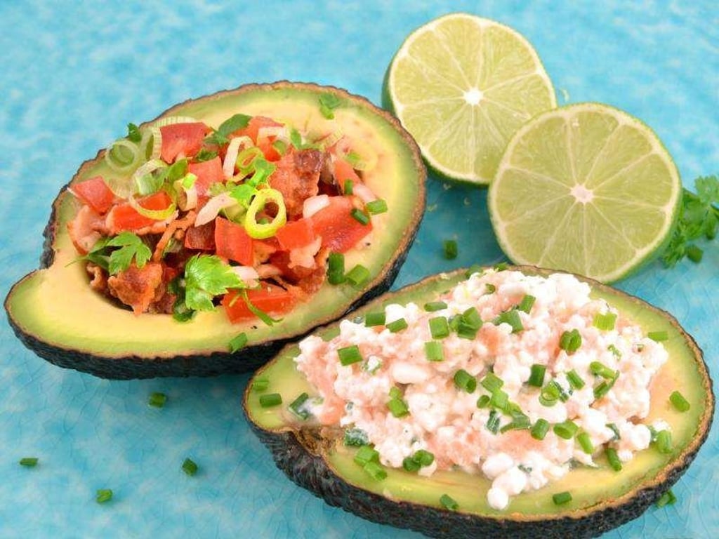 Tomaten-Salat mit Limette und gebratenem Bacon zieren die eine Avocadohälfte, Frischkäse mit geräuchertem Lachs die andere. Foto: Julia Uehren/www.loeffelgenuss.de