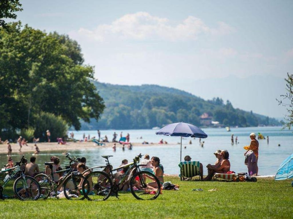 Badegäste liegen am Starnberger See an einem Strand. Der Landkreis ist der reichste in Deutschland. Foto: Lino Mirgeler