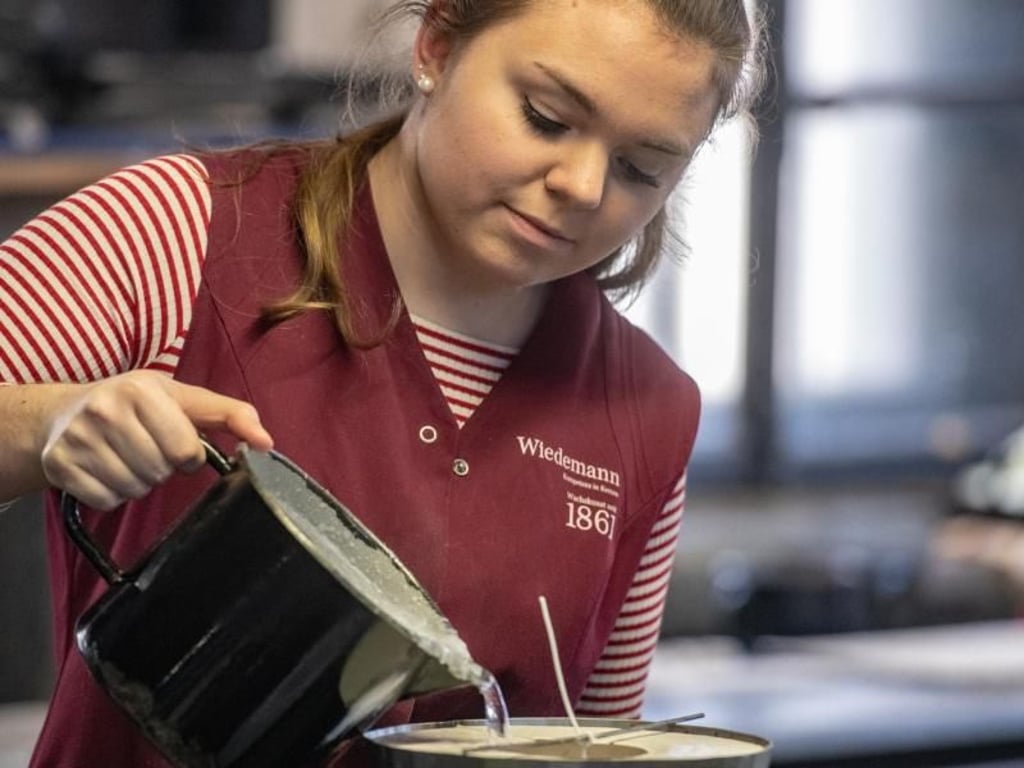 Alles Handarbeit: Franziska Hüttinger lernt in ihrem Betrieb, wie heißes, flüssiges Wachs bei der Kerzenherstellung richtig zu handhaben ist. Foto: Armin Weigel