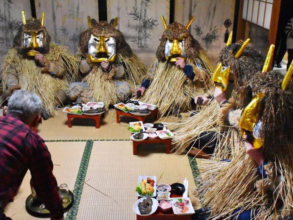 Ein Mann serviert in Akita (Japan) den «Namahage-Dämonen» ein Festmahl. Mit ihren Dämonenmasken und der Strohkleidung werden die «Namahage» als göttliche Boten behandelt, die den Menschen durch einen Besuch zum Jahreswechsel Segen bringen. Foto: kyodo