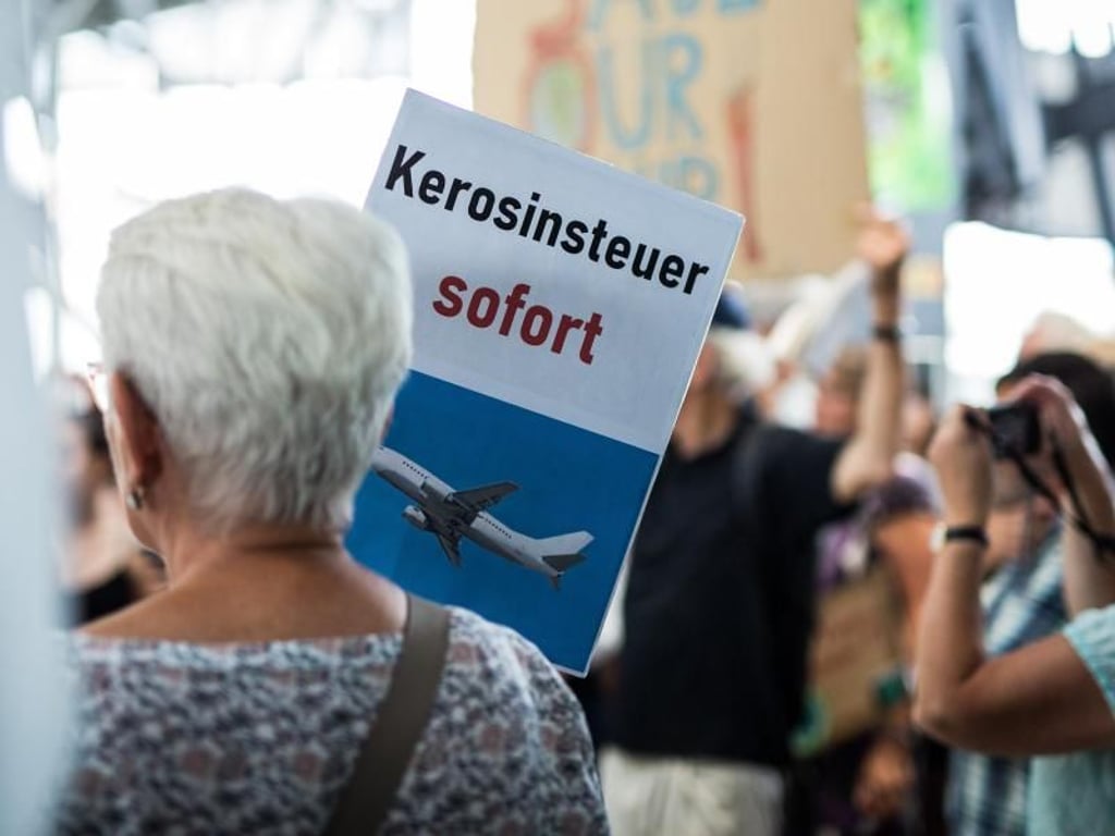 «Kerosinsteuer sofort» steht auf dem Schild einer Aktivistin. Foto: Christoph Schmidt