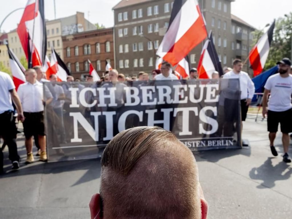 Vor dem Zug der Neonazi-Demonstration anlässlich des 31. Todestages von Rudolf Heß kniet ein Mann mit einer Fisur, die bei Neonazis üblich ist. Foto: dpa