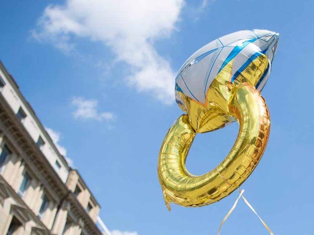 Eine Frau hält einen Luftballon in Form eines Eherings in der Hand. Foto: Sebastian Gollnow/Archiv