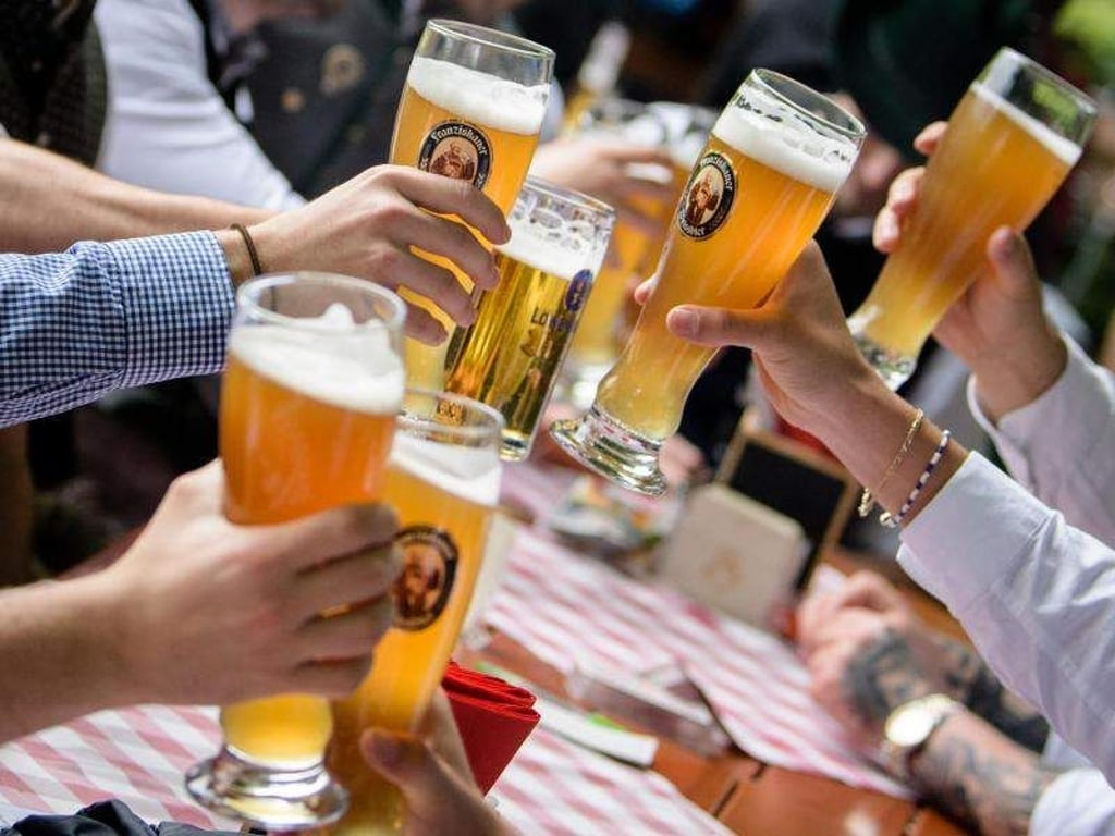 Eine Gruppe stößt im Biergarten eines Wirtshauses mit ihren Weißbiergläsern an. Foto: M. Balk/Archivbild