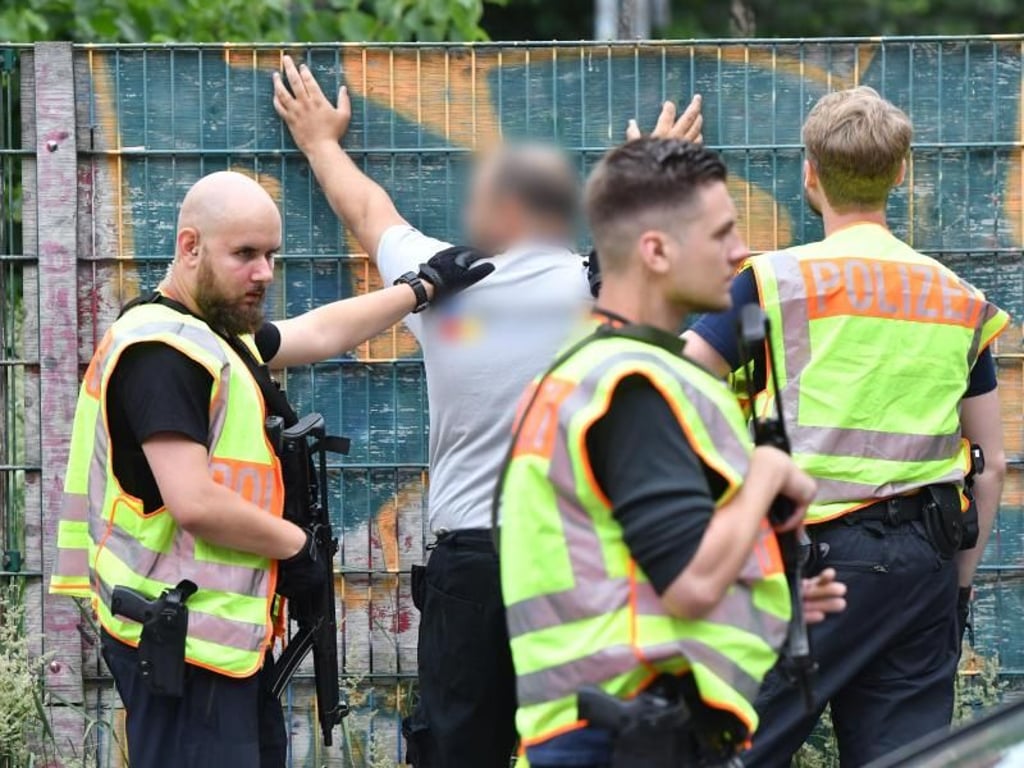 Polizisten durchsuchen eine Mann an einer Berliner Grundschule im Bezirk Mitte. Foto: Paul Zinken