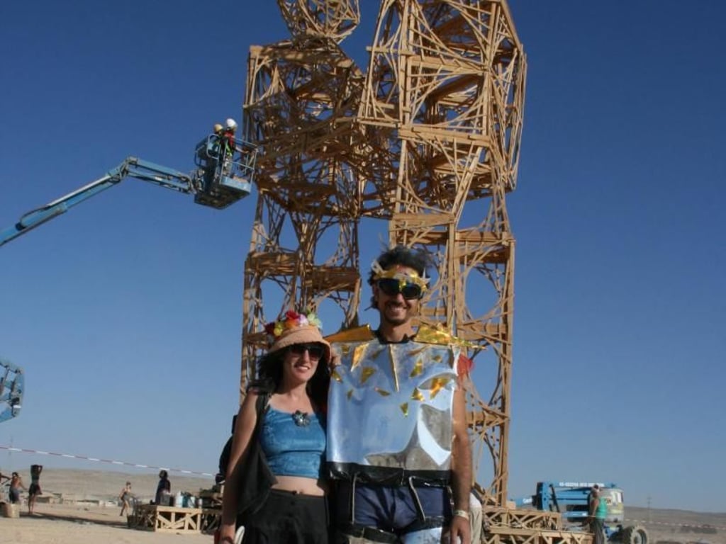 Der Künstler Daniel Polykov und seine gute Freundin Shani Wisse stehen vor den beiden rund 20 Meter hohen Statuen, die jedes Jahr als ein Höhepunkt des Festes verbrannt werden. Foto: Stefanie Järkel