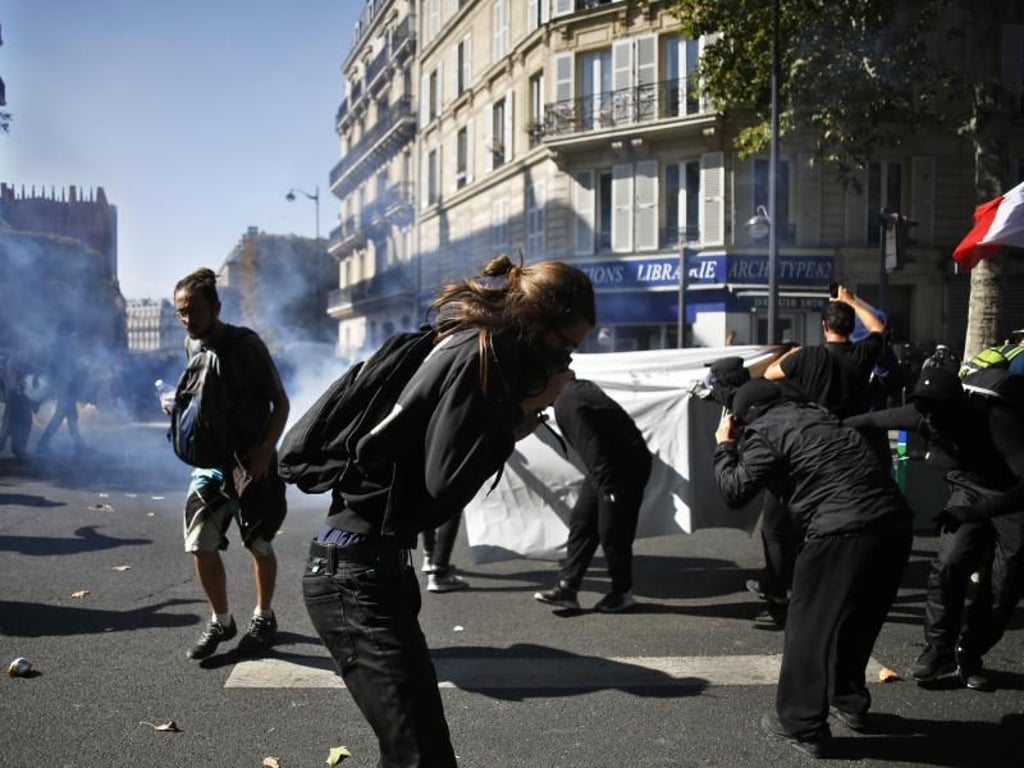 Demonstranten versuchen, sich vor dem Tränengas der Polizei zu schützen. Foto: Thibault Camus/AP