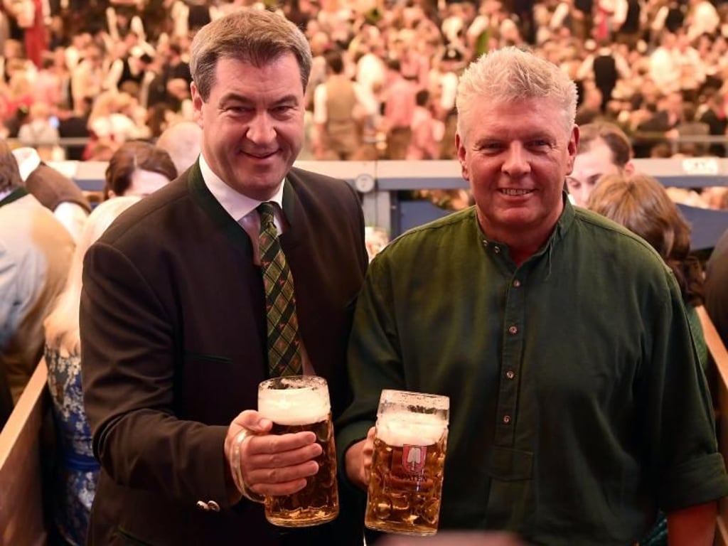 Markus Söder (l, CSU) und Dieter Reiter (SPD) stoßen mit zwei Masskrügen an. Foto: Peter Kneffel