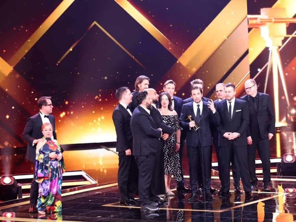 Christine Urspruch und Jan Josef Liefers übergeben die Goldenen Kamera für die Kategorie «Beste Miniserie/Mehrteiler» an die Darsteller und Macher der Fernsehserie «4Blocks». Foto: Christian Charisius