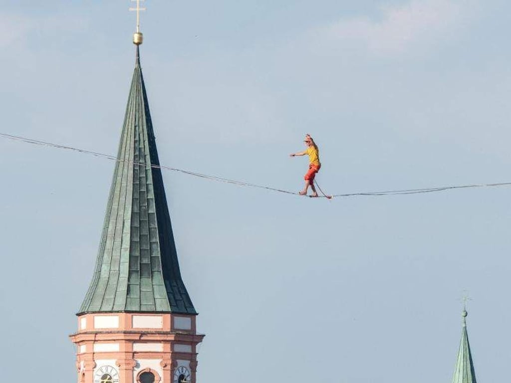 Lukas Irmler geht über den Dächern der Altstadt von Straubing (Bayern) auf einer Slackline entlang. Foto: Armin Weigel