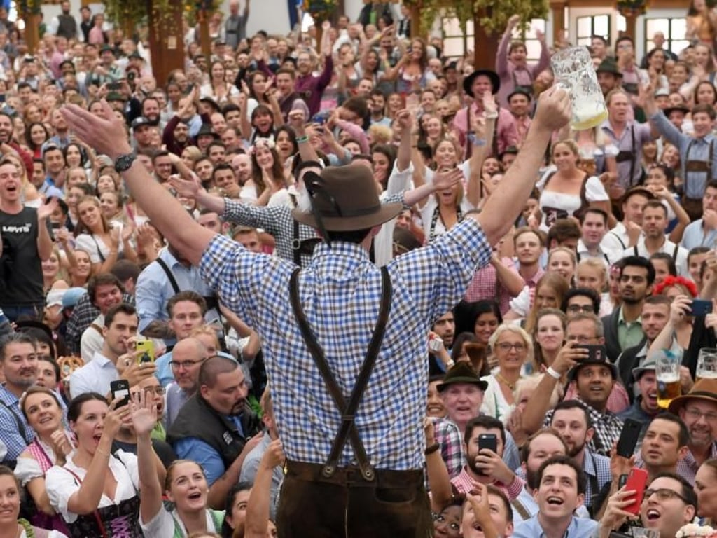 Ein Gast steht im Hobräuzeit auf dem Oktoberfest auf einem Tisch, nachdem er eine Maß Bier auf Ex getrunken hatte. Foto: Felix Hörhager