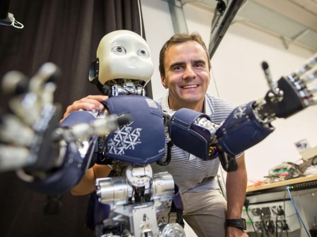 Professor Jan Peters steht hinter dem Roboter iCub. Foto: Frank Rumpenhorst