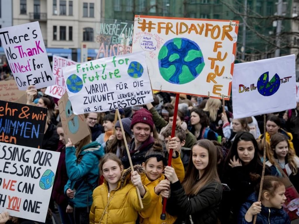Jugendliche Teilnehmer der Klima-Kundgebung «Fridays for Future» stehen mit Plakaten am Berliner Invalidenpark und fordern eine bessere Klimapolitk. Foto: Christoph Soeder