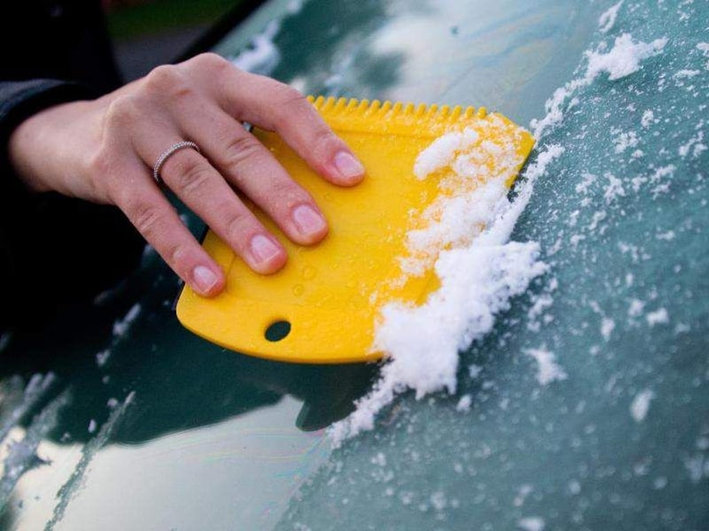 Eine Frau kratzt Eis. Foto: Julian Stratenschulte/Archiv