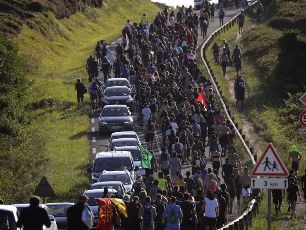 Demonstranten marschieren auf einer Straße in der Nähe eines Zeltlagers während eines Protest gegen den G7-Gipfel. Foto: Emilio Morenatti/AP